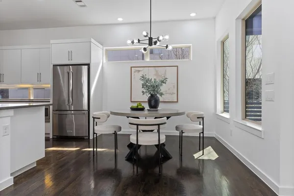 a kitchen with stainless steel appliances a dining table chairs refrigerator and microwave