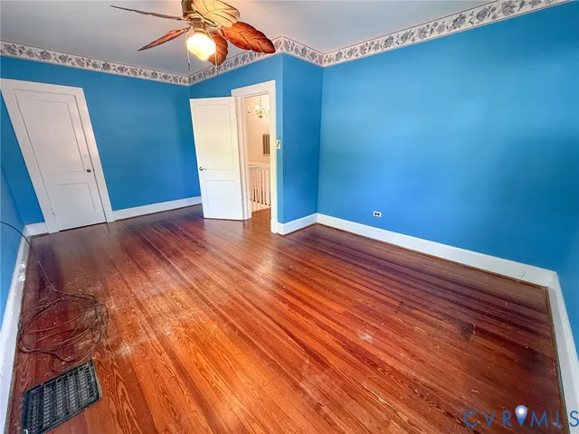 a view of an empty room with window and wooden floor