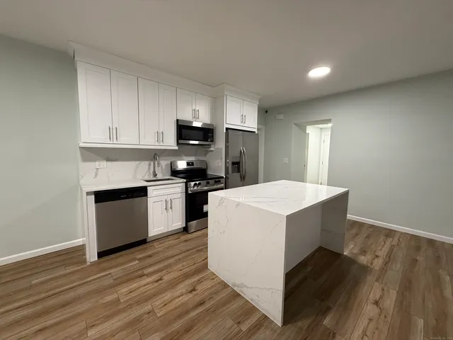 a kitchen with kitchen island a sink stainless steel appliances and cabinets