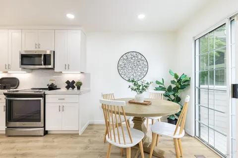 a kitchen with stainless steel appliances a dining table chairs and microwave