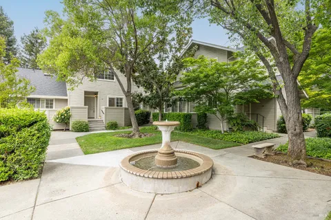 a front view of a house with a yard garage and fountain
