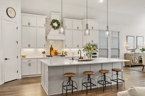 a kitchen with stainless steel appliances kitchen island granite countertop a table chairs in it and white cabinets
