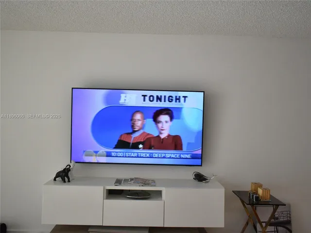 a living room with a flat screen tv and dresser