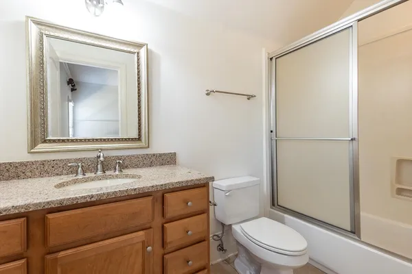 a bathroom with a granite countertop sink toilet and shower
