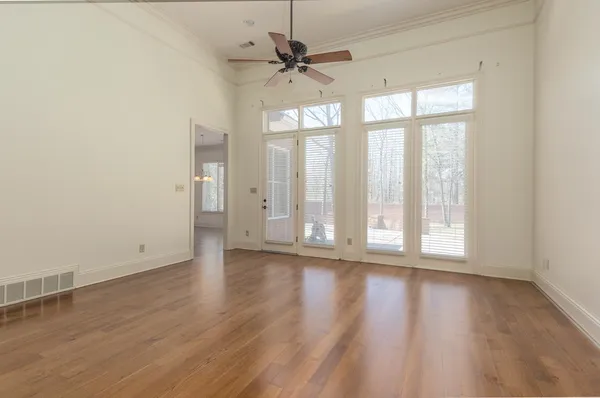 an empty room with wooden floor and windows