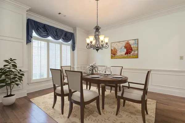 an empty room with wooden floor chandelier and windows