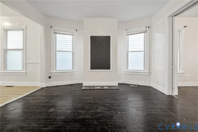 an empty room with wooden floor and windows