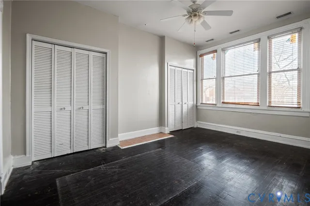 an empty room with wooden floor fan and windows