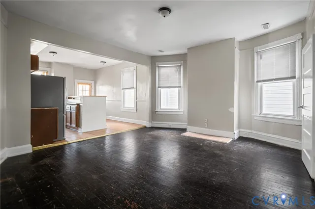 a view of an empty room with window and wooden floor