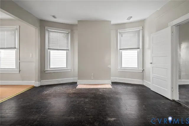 an empty room with wooden floor and windows