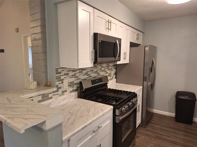 a kitchen with stainless steel appliances granite countertop a stove microwave and sink
