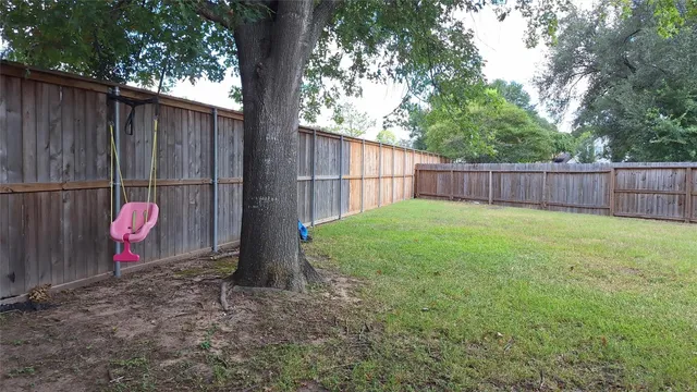 a view of a backyard with a large tree and wooden fence