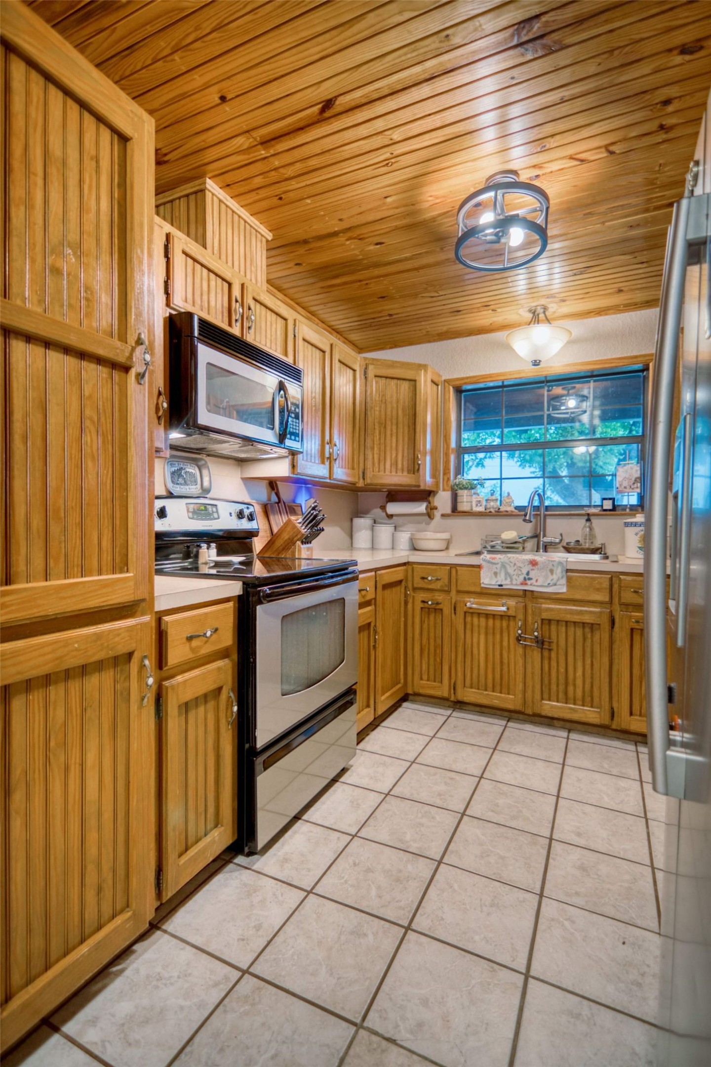 904 Bluebonnet Road Mason, TX 76856 - Photo 13 of 28 Kitchen featuring wood plank ceiling, wood cabinetry, stainless steel oven, stainless steel microwave, and tiled flooring