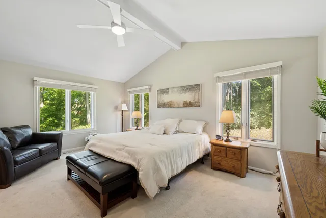 a bedroom with a bed couch and windows