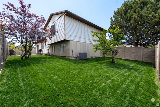 3689 Lasso Loop Circle Magna, UT 84044 - Photo 20 of 26 Expansive backyard featuring a lush lawn, established trees, and durable stone-look fencing