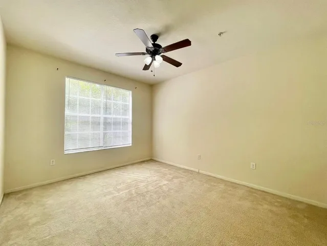 an empty room with windows and fan
