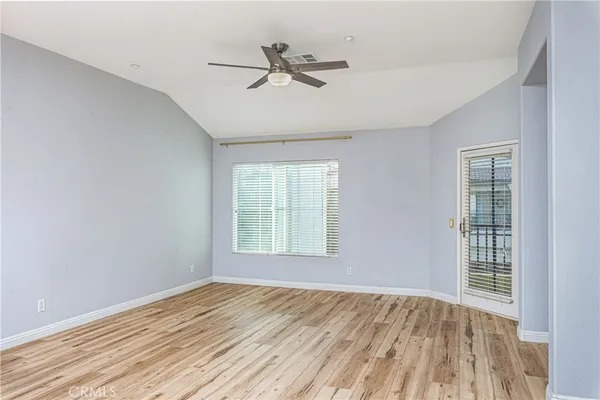 an empty room with wooden floor fan and windows