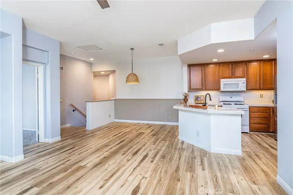 a kitchen with granite countertop wooden floors appliances and cabinets