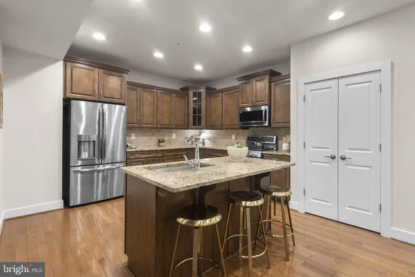 a kitchen with kitchen island granite countertop wooden cabinets and stainless steel appliances