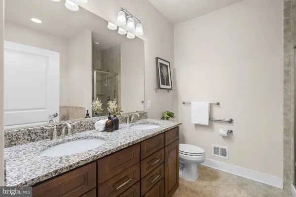 a bathroom with a granite countertop sink a toilet and a mirror