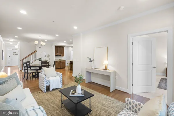 a living room with furniture kitchen view and a wooden floor