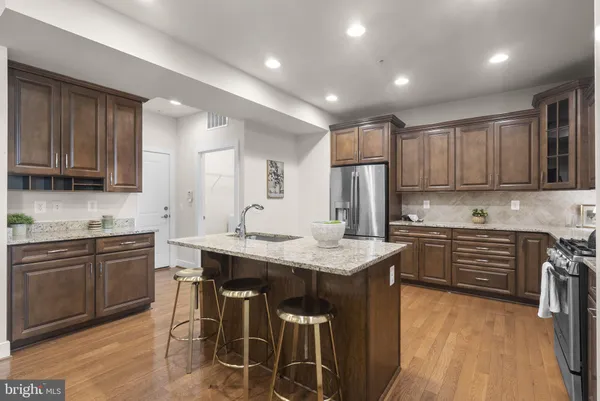 a kitchen with stainless steel appliances granite countertop a stove top oven a sink dishwasher a dining table and chairs with wooden floor