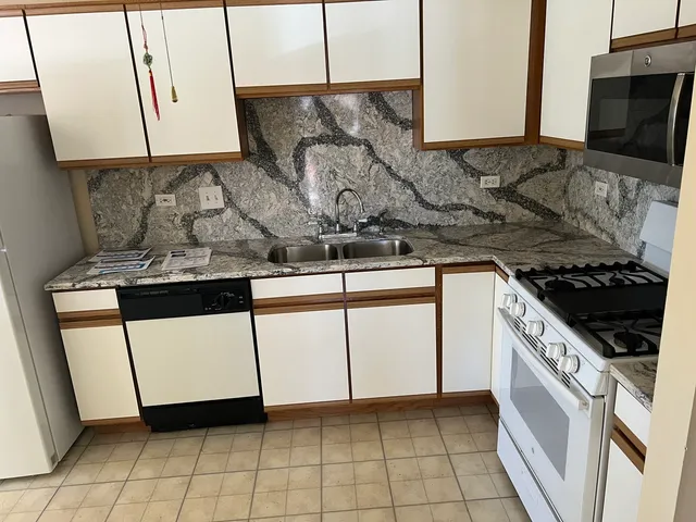 a kitchen with stainless steel appliances granite countertop a stove a sink and a microwave