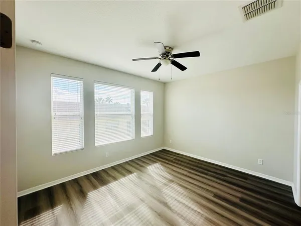 a view of empty room with wooden floor and fan