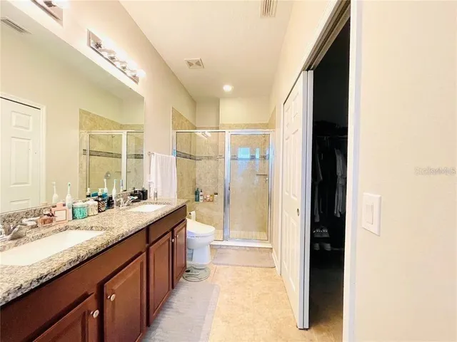 a large bathroom with a granite countertop sink a toilet a mirror and shower