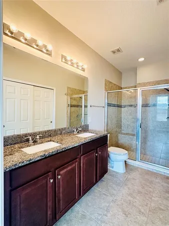 a bathroom with a granite countertop sink mirror and toilet