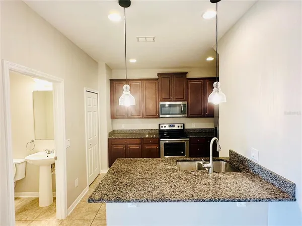 a kitchen with kitchen island granite countertop a sink stove and refrigerator