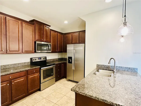 a kitchen with kitchen island granite countertop a sink stainless steel appliances and cabinets