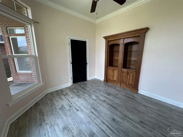 an empty room with wooden floor chandelier fan and windows