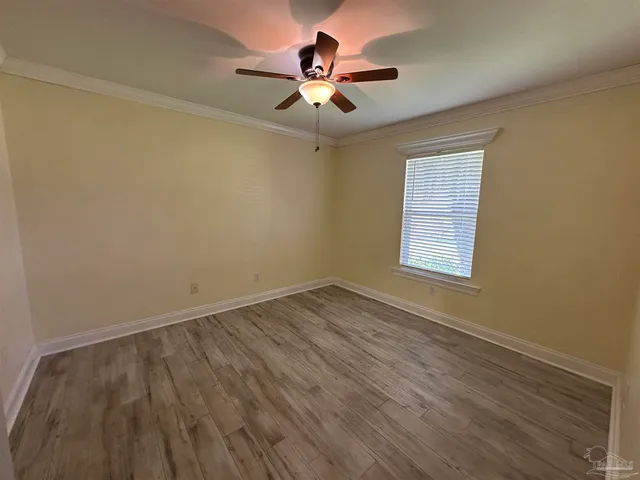 an empty room with wooden floor fan and windows