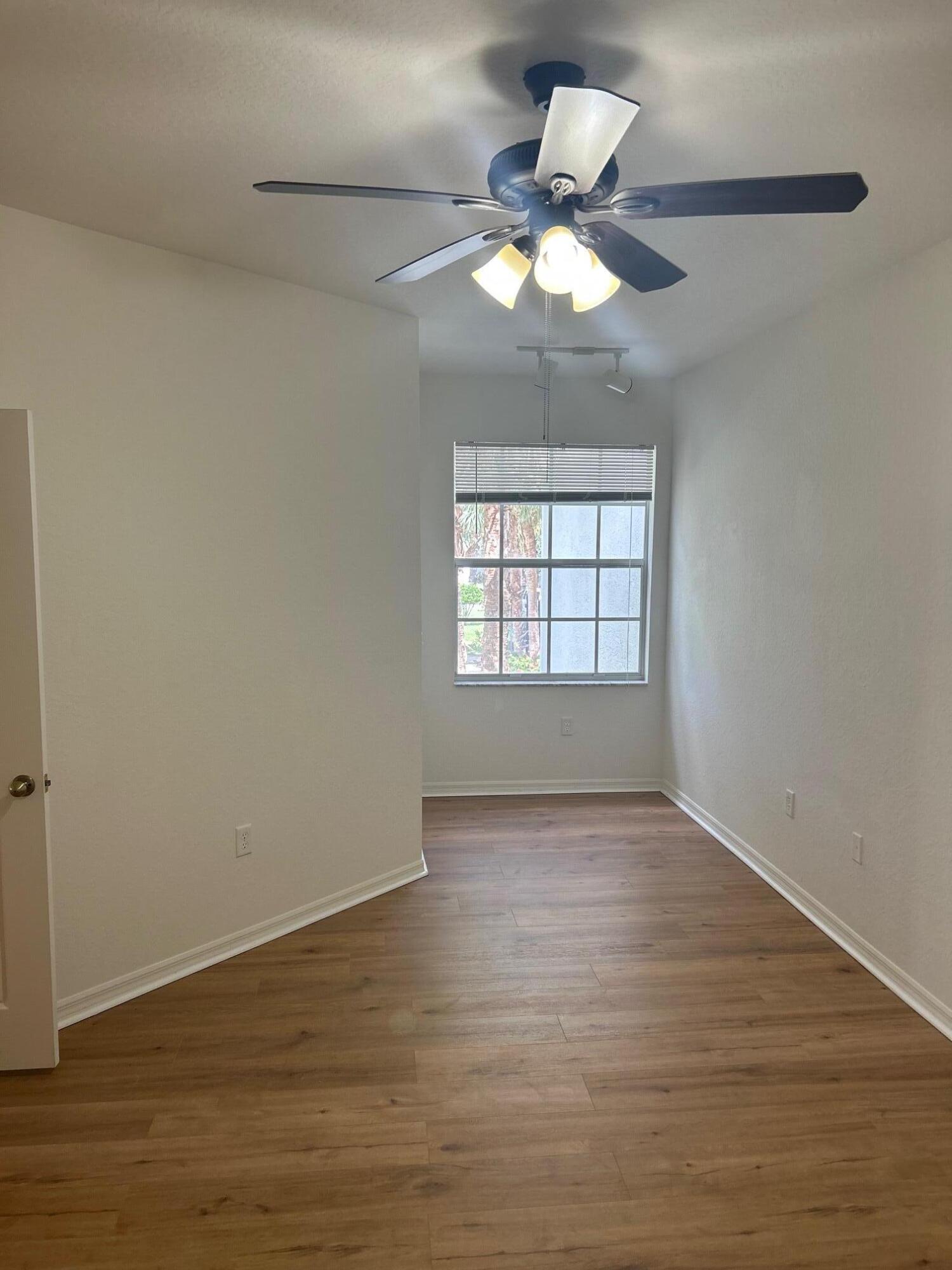 272 Southeast Kitching Circle Stuart, FL 34994 - Photo 5 of 23 an empty room with wooden floor chandelier fan and windows