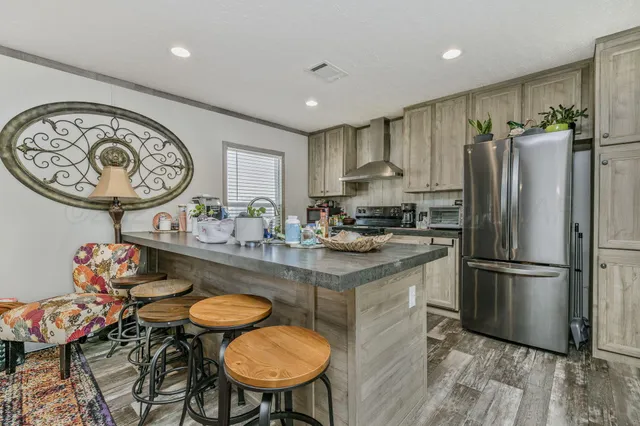 a kitchen with stainless steel appliances granite countertop a dining table chairs refrigerator sink and cabinets