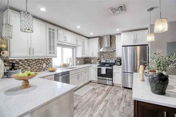 a kitchen with stainless steel appliances granite countertop a refrigerator a sink dishwasher a oven and a dining table with wooden floor