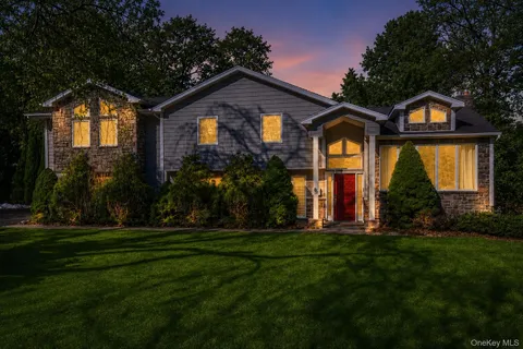 a view of a house with a yard and large tree