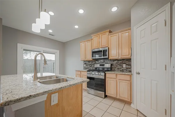 a kitchen with granite countertop a sink a chandelier and living room view
