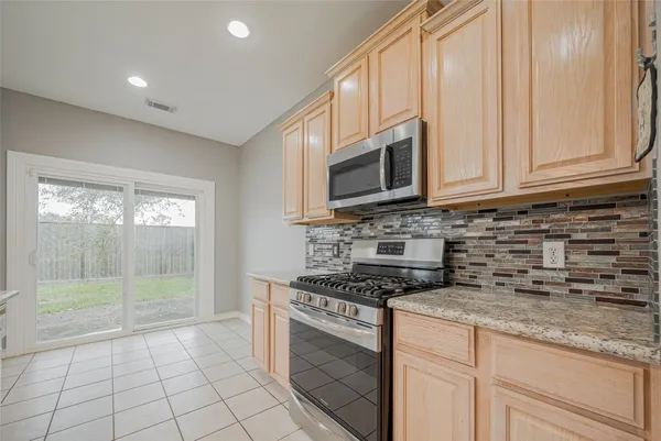 a kitchen with granite countertop white cabinets and stainless steel appliances