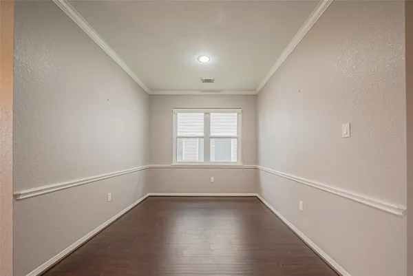 a view of an empty room with wooden floor and windows
