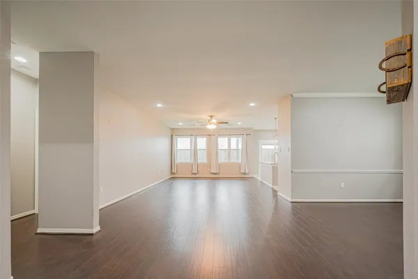 an empty room with wooden floor and ceiling fan