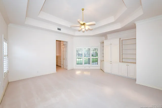 an empty room with windows and ceiling fan