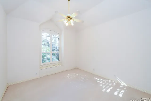an empty room with windows and chandelier fan