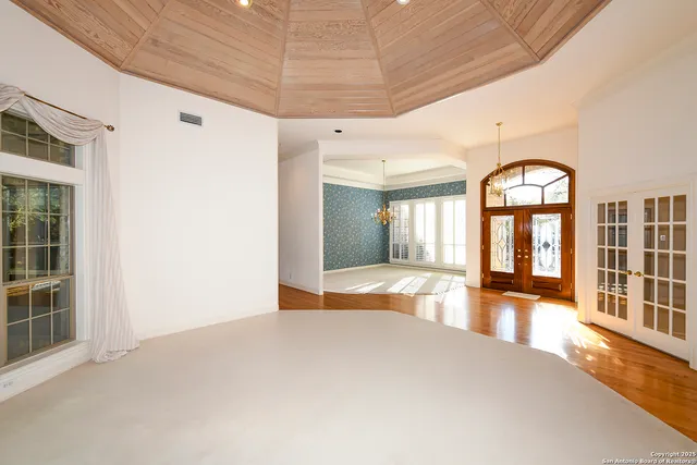 a view of an empty room with window and a kitchen view