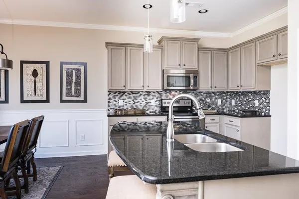 a kitchen with granite countertop a sink a stove and cabinets