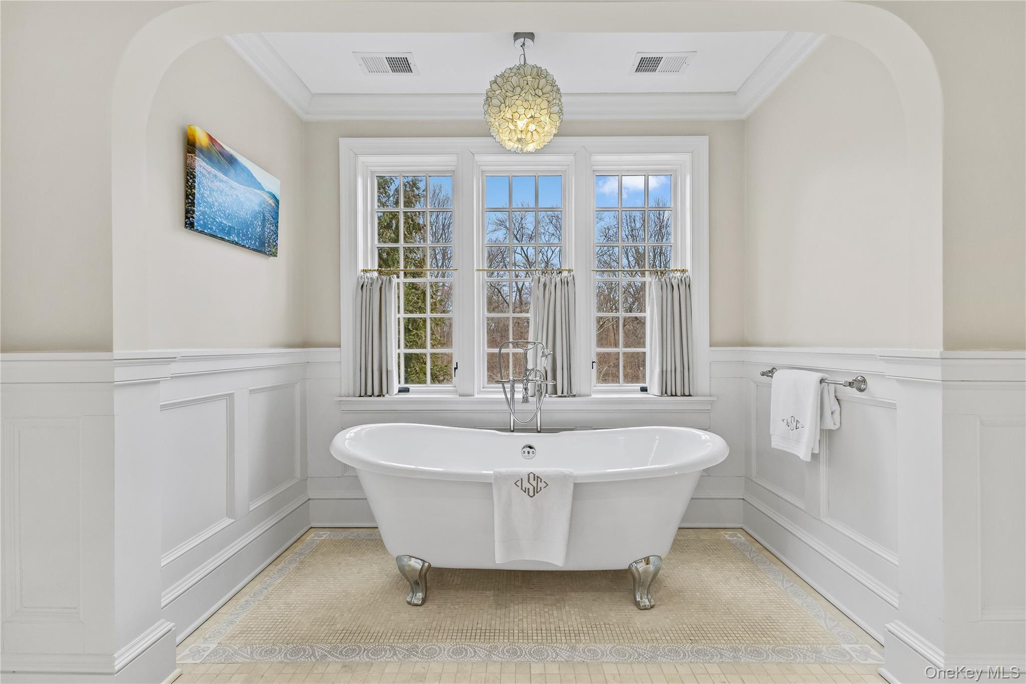 19 Park Drive South Rye, NY 10580 - Photo 27 of 42 The primary suite offers a serene sanctuary centered around a classic clawfoot soaking tub framed by elegant wainscoting and a sprawling triple-window view of the tranquil grounds.