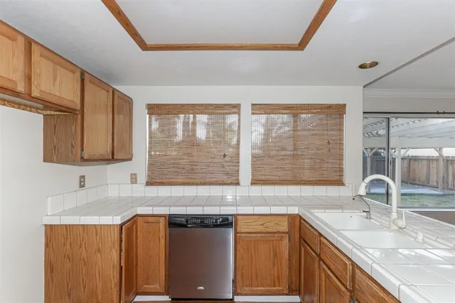 a kitchen with stainless steel appliances granite countertop a sink a stove and a wooden cabinets