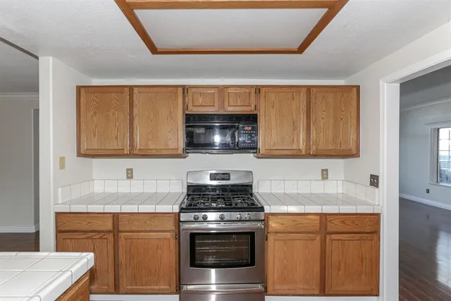a kitchen with granite countertop a sink stove and microwave