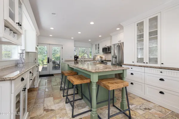 a kitchen with stainless steel appliances kitchen island granite countertop a table chairs sink and cabinets